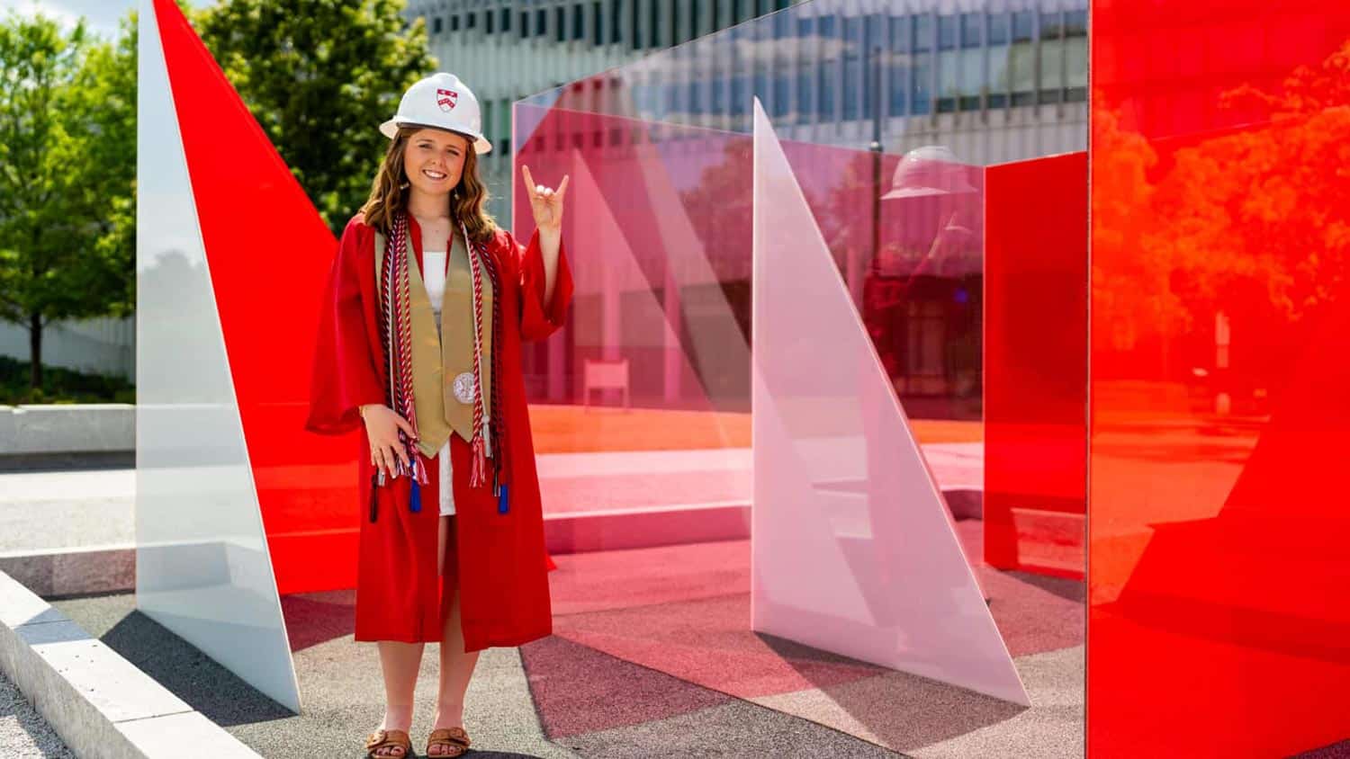 A student wearing a red graduation cap looks into the future.