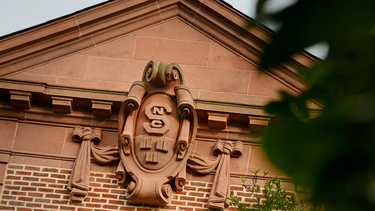 The facade of Holladay Hall shows an old, ornate NC State seal.