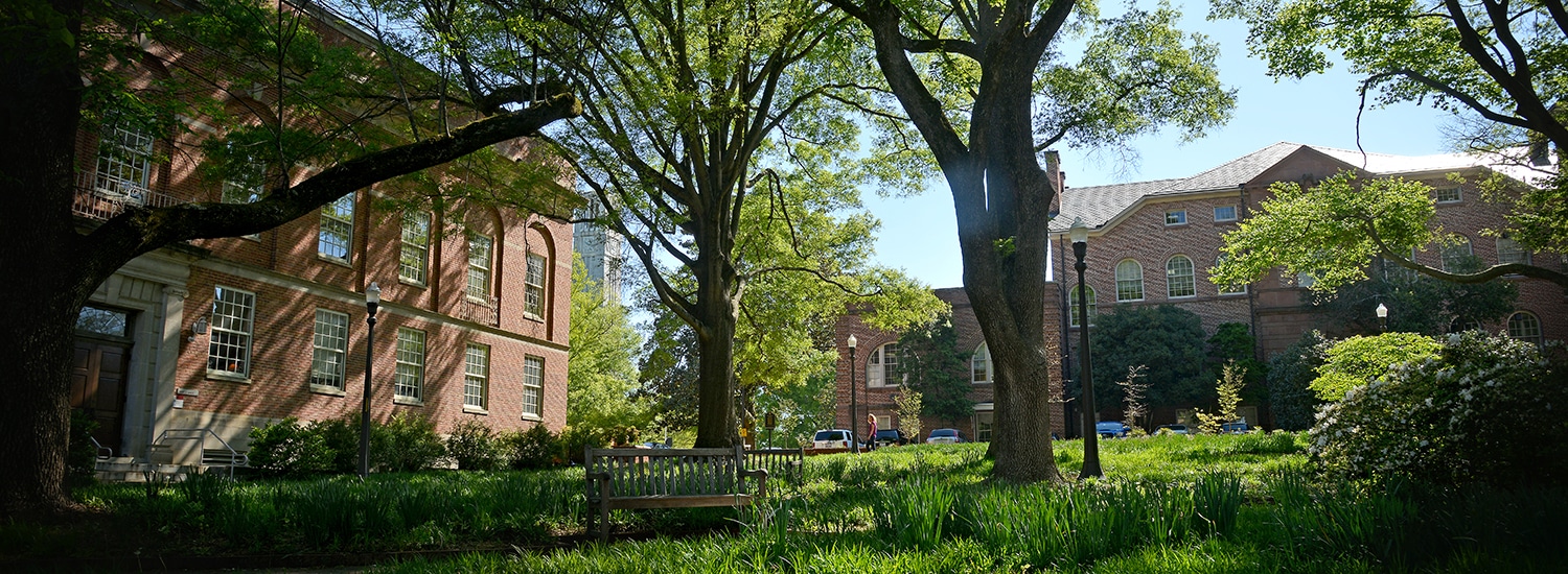 A shady view of Mary Yarbrough Court, surrounded by historic NC State buildings including Holladay Hall.