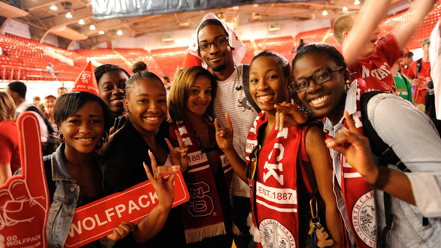Student from the 2010s wear Wolfpack scarves during NC State's 125th birthday party in Reynolds Coliseum. 